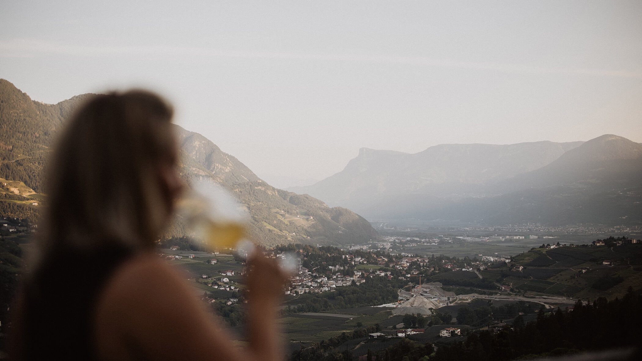 Eine Frau blickt hinunter ins Tal auf Meran